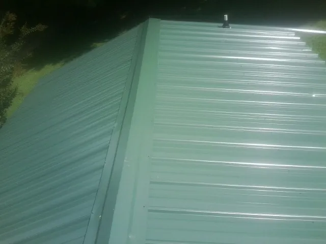 New green metal panels meeting at the ridge of a roof — Flat Roof Repair work by our crew in Pipe Creek