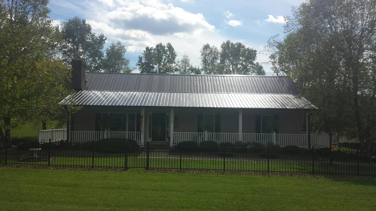 Gray metal roof on a brick ranch with a full width front porch — Gutter Guard Installation work by our crew in Pipe Creek