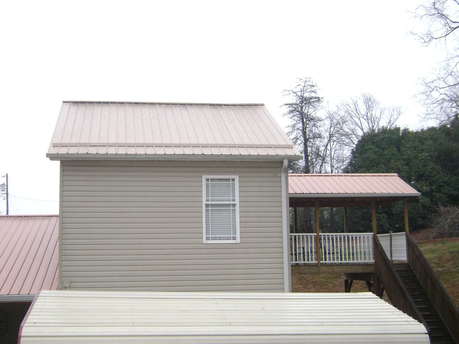 Tan metal roofs on a two story addition and attached porch, from a Roof Replacement job in Pipe Creek