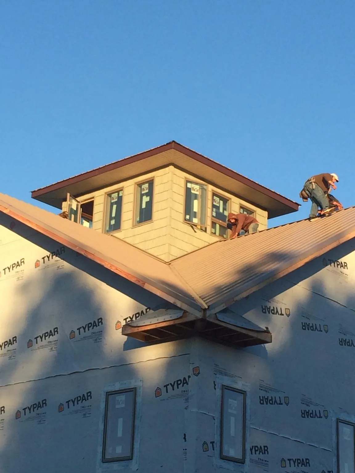 Roofers working around a rooftop cupola on a new metal roof at sunset — Roof Waterproofing in Pipe Creek by Roofing Brothers